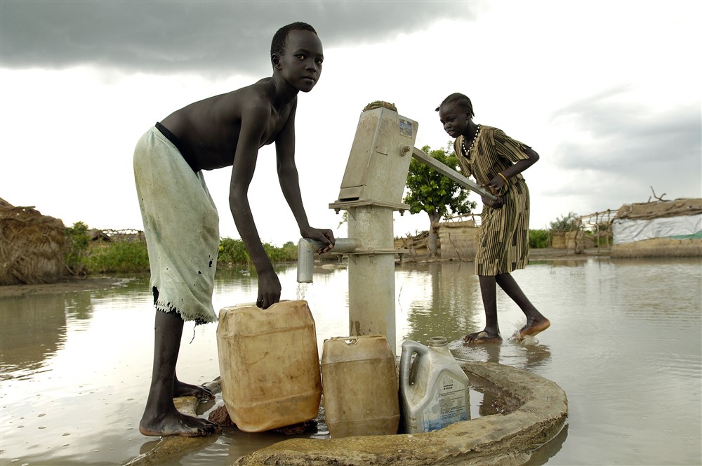 Children displaced by flooding in South Sudan collect water from a submerged hand pump. Photo UNMIS