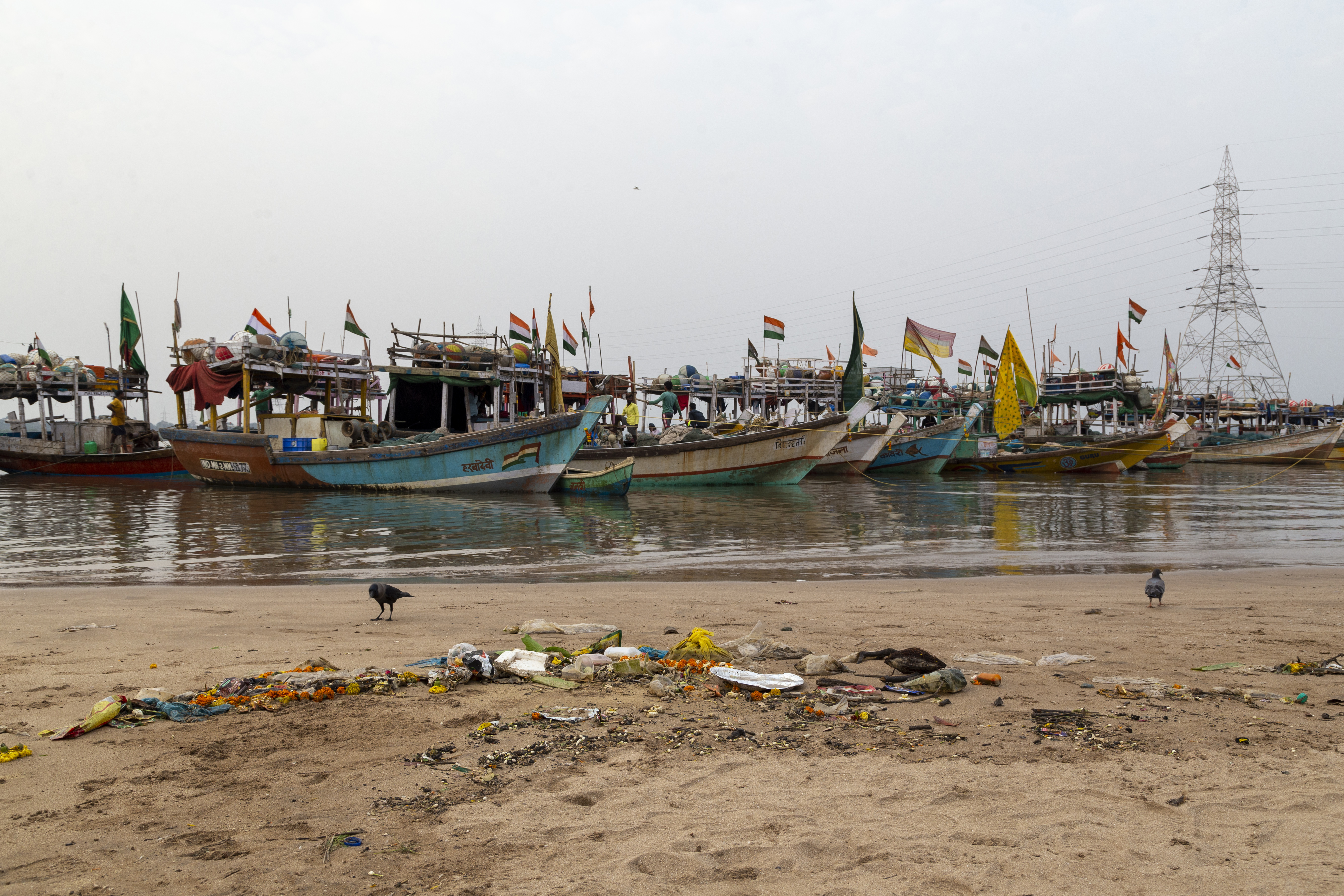 Plastic waste on beach, fishingboats in the background