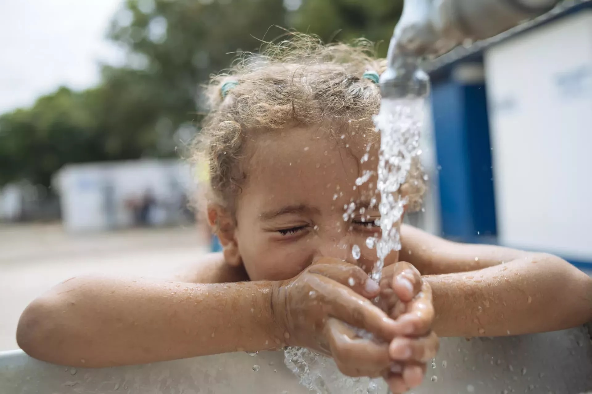 Girl drinking water from tap outdoor